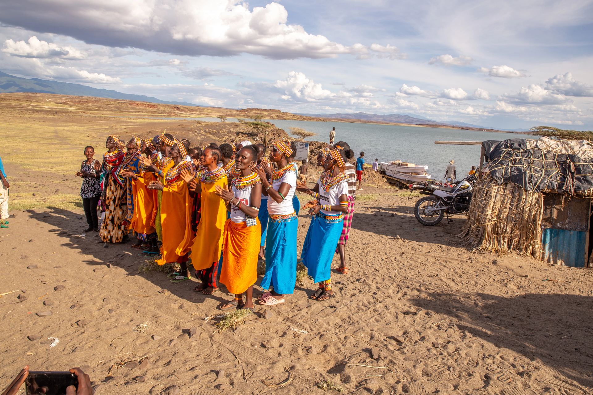 Women in traditional beadwork dancing in formation on the shores of Lake Turkana